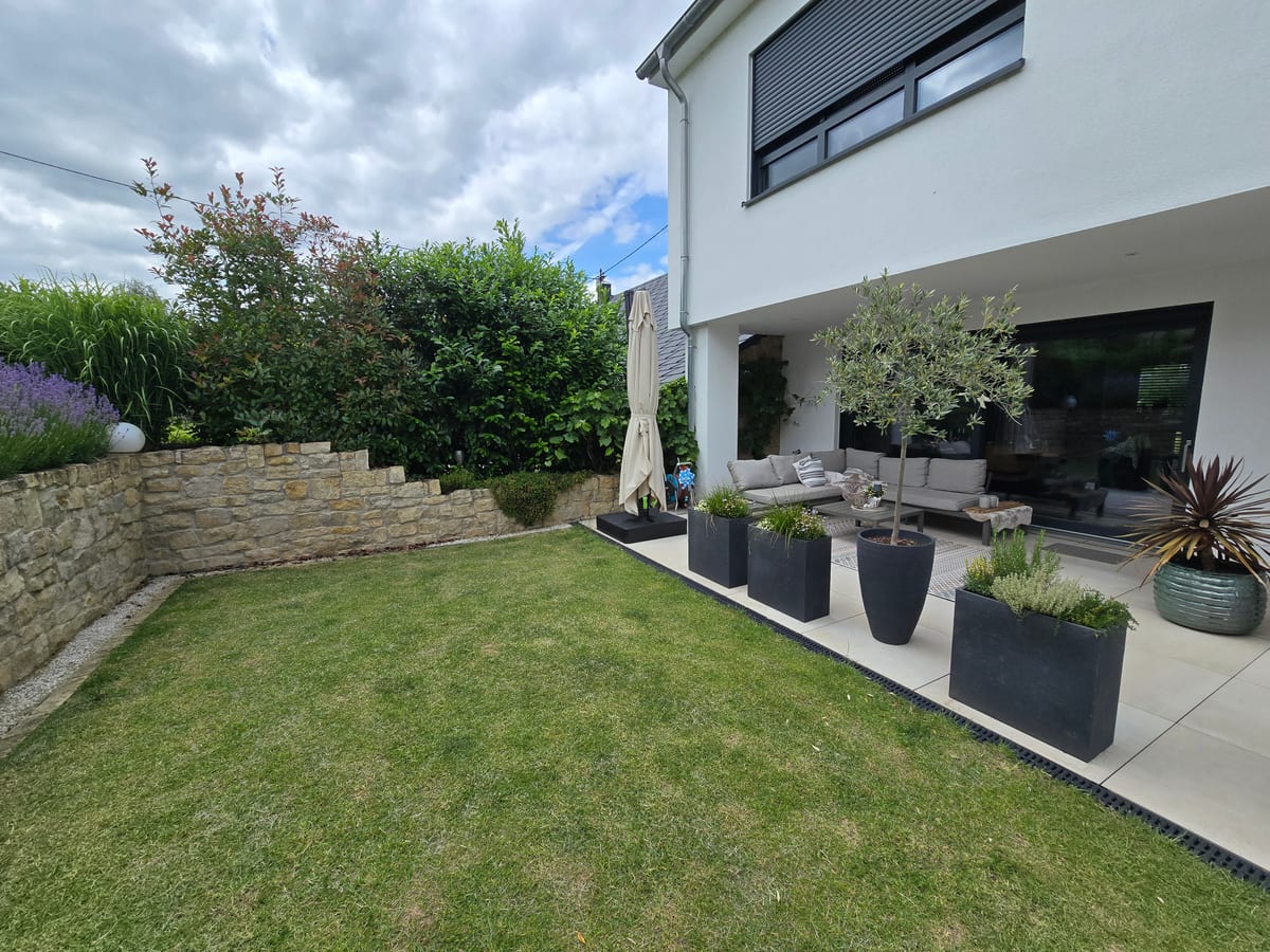 Garten mit Natursteinmauer und moderner Terrasse am Wohnhaus